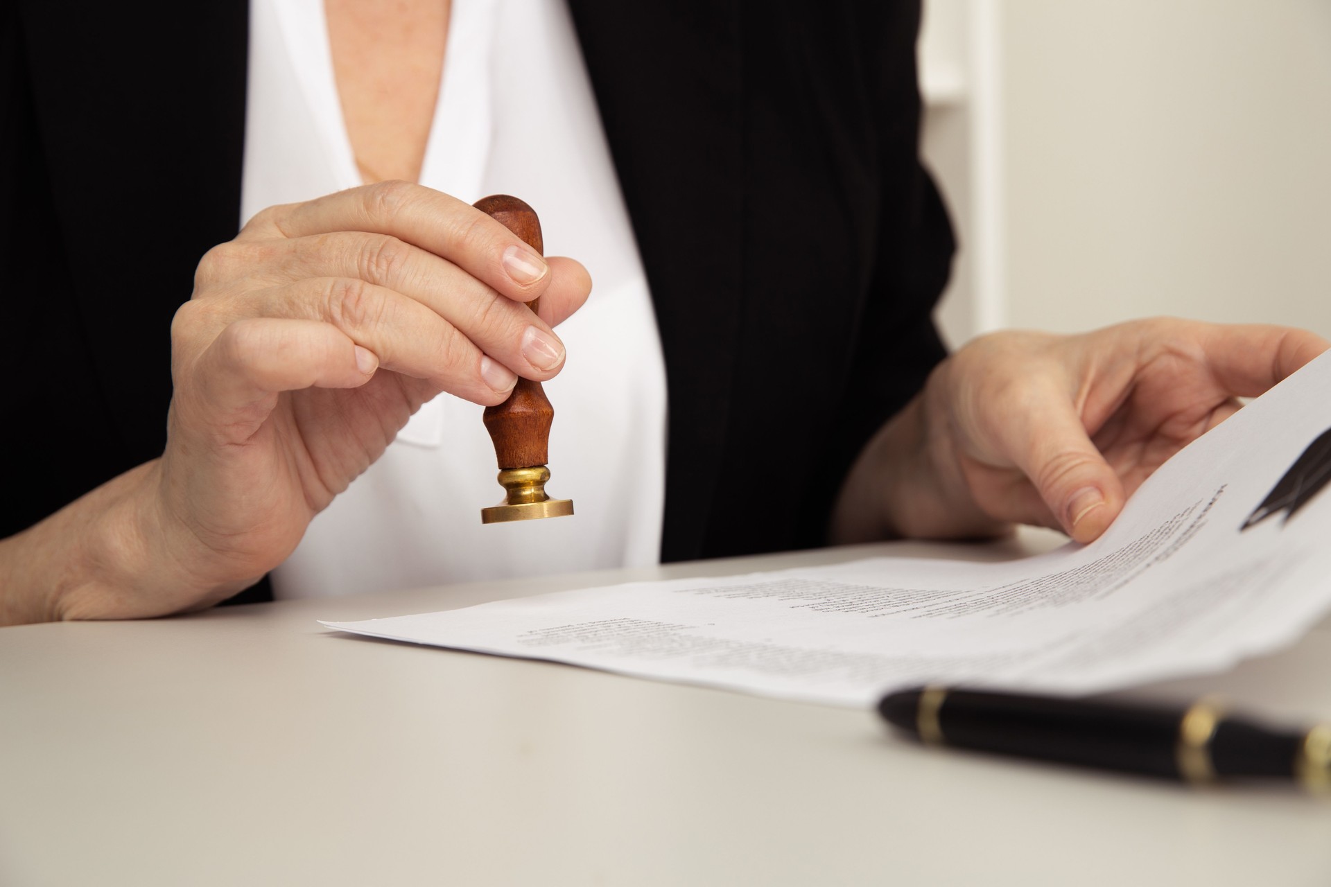 Closeup view of female hand holding stamp and notarized paper.